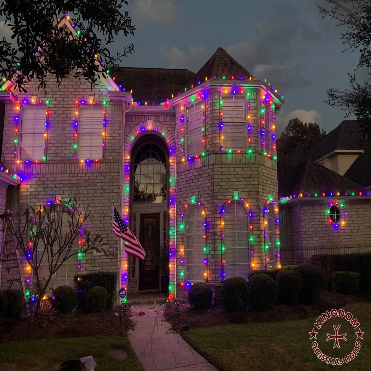 House decorated with colorful Christmas lights and an American flag.