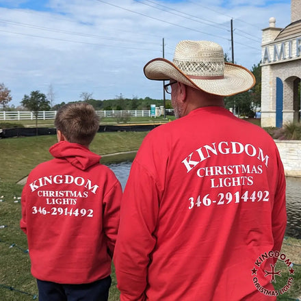Two people wearing red shirts with 'Kingdom Christmas Lights' branding and contact information.