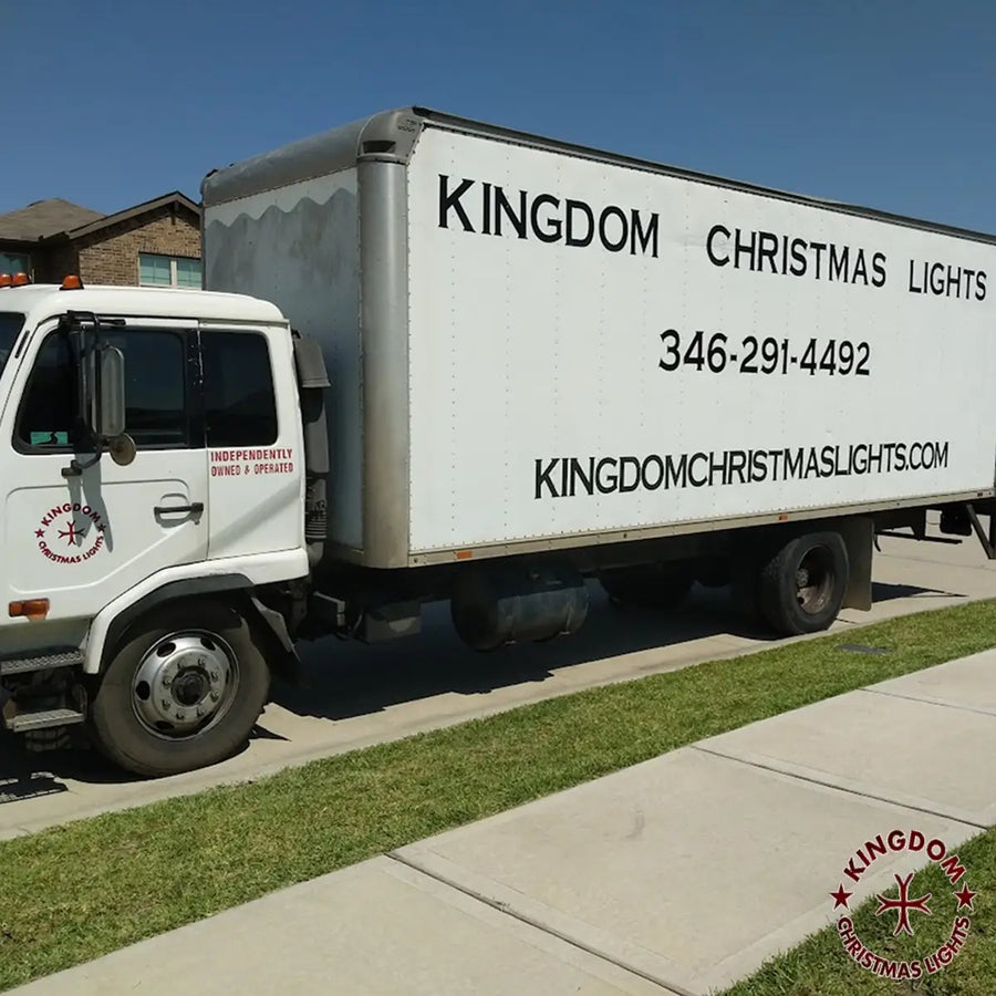 A white service truck with 'Kingdom Christmas Lights' branding, indicating a commercial holiday lighting service.