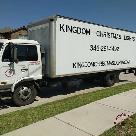 A white service truck with 'Kingdom Christmas Lights' branding, indicating a commercial holiday lighting service.