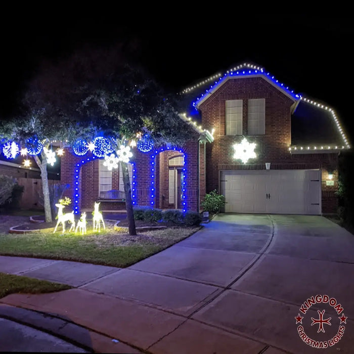 Brick house decorated with Christmas lights and outdoor figures on a dark night.