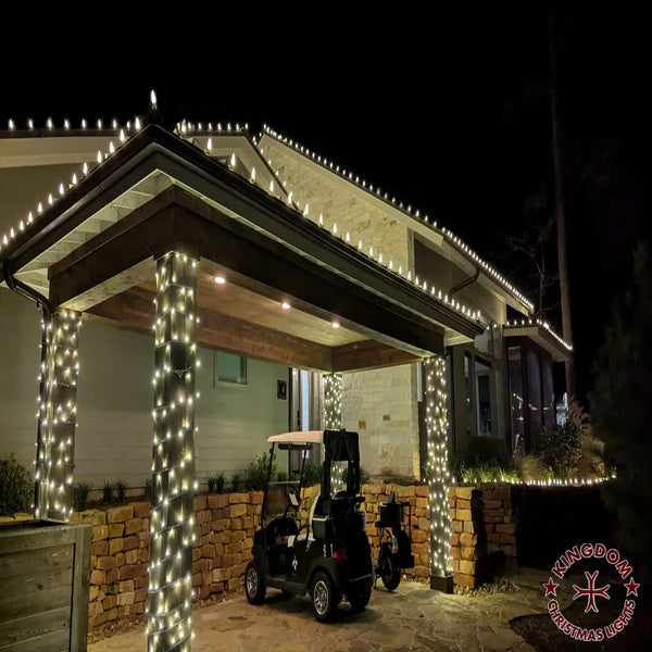 Gated entrance with decorative string lights and a golf cart at night.