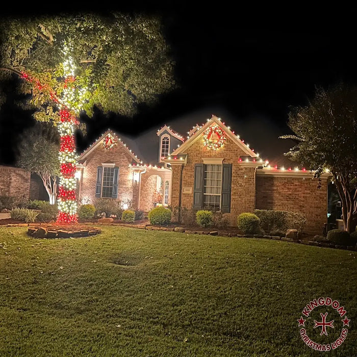 House decorated with Christmas lights and wreaths at night.