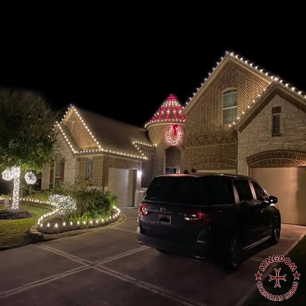 House decorated with Christmas lights at night, with a car parked in front.