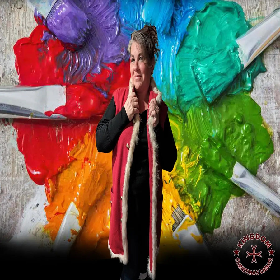 Person holding a paintbrush in front of a colorful abstract painting with Kingdom Christmas logo.