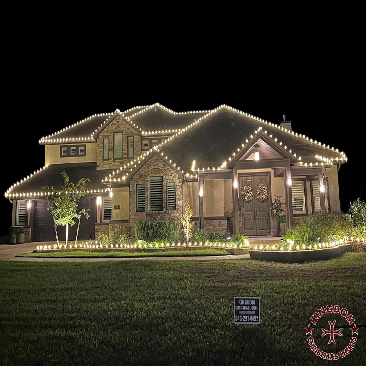 Tomball home with warm white lights tracing multiple roof peaks and the front planting-bed border.