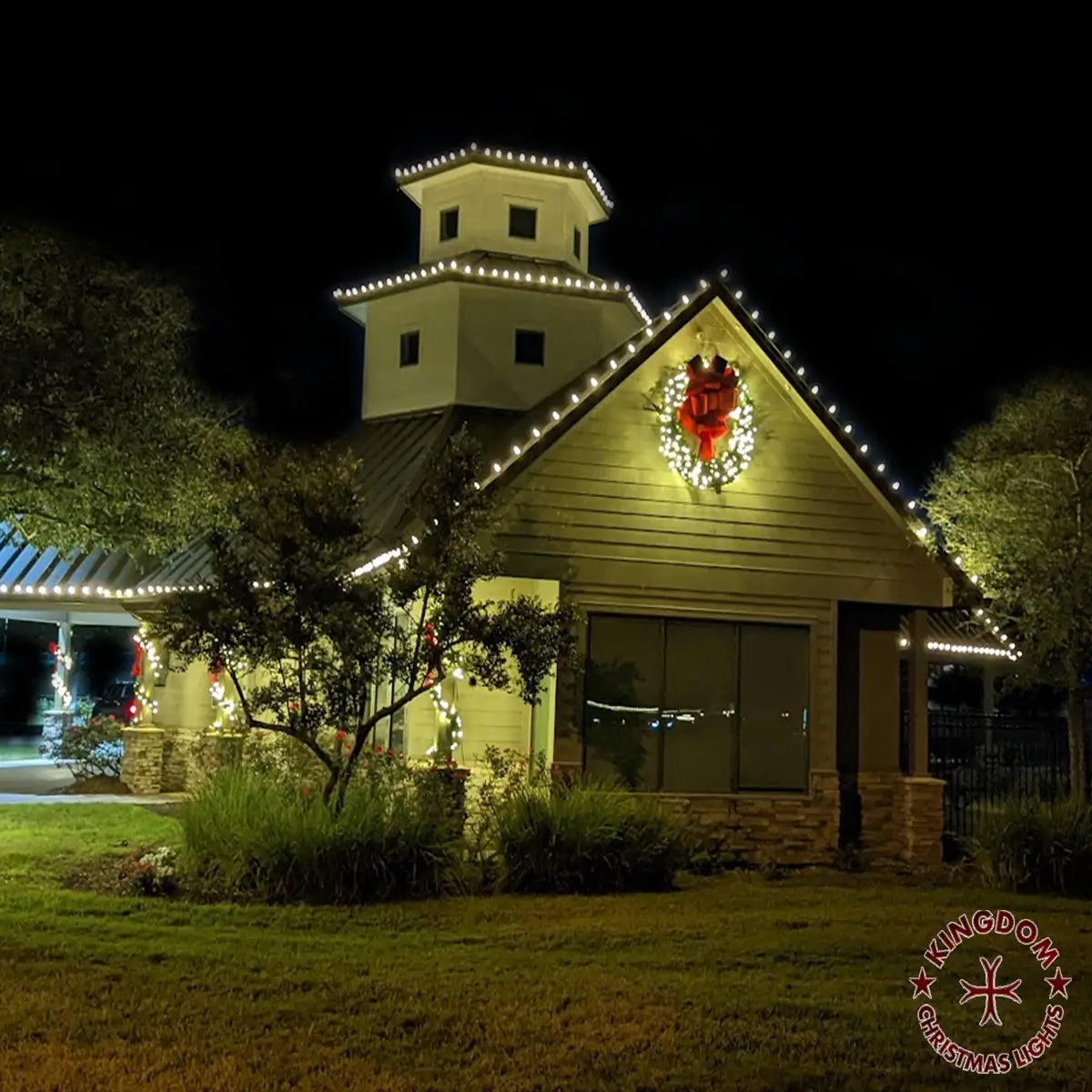 Community building outlined with warm white Christmas lights and a wreath
