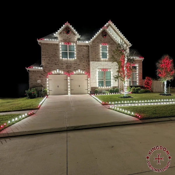 Two-story house decorated with Christmas lights and wreaths at night.