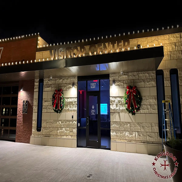 Building entrance with wreaths and a sign at night