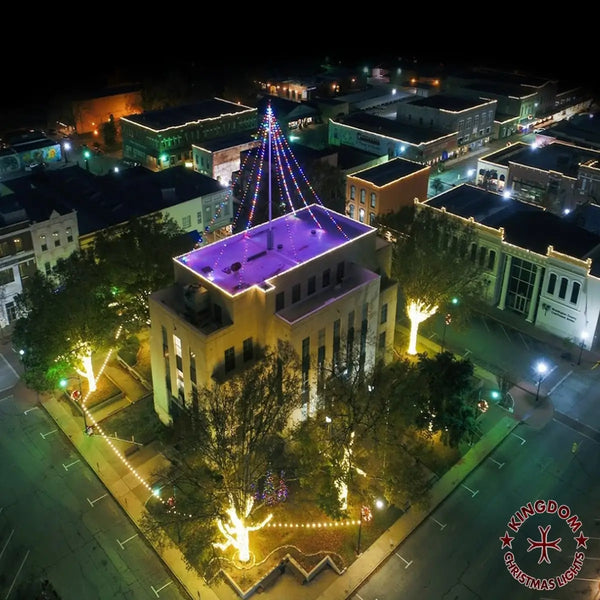 Aerial view of a building with a Christmas light display on its roof at night.