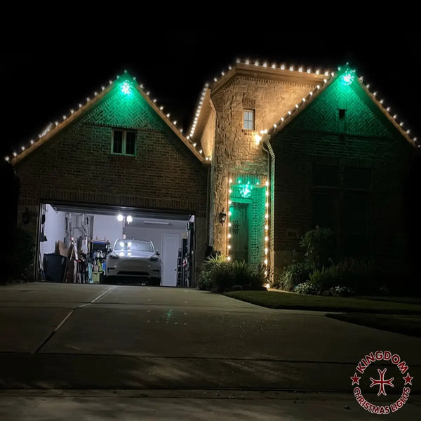House exterior with festive lights during nighttime, featuring a garage and stone tower.