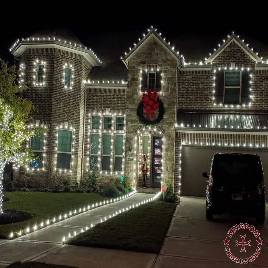 House decorated with Christmas lights and a wreath on a dark night.