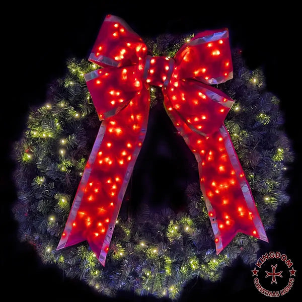 Christmas wreath with a large red bow featuring LED lights on a dark background.