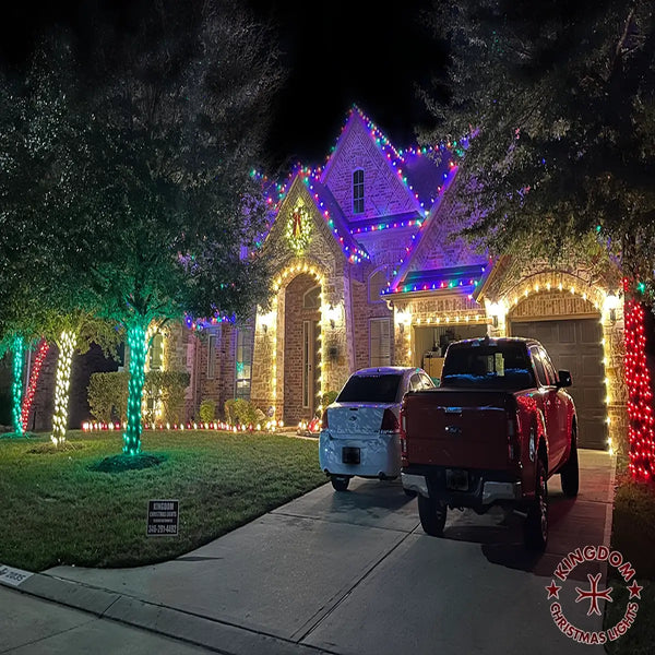 House decorated with Christmas lights at night, with a truck parked in front.