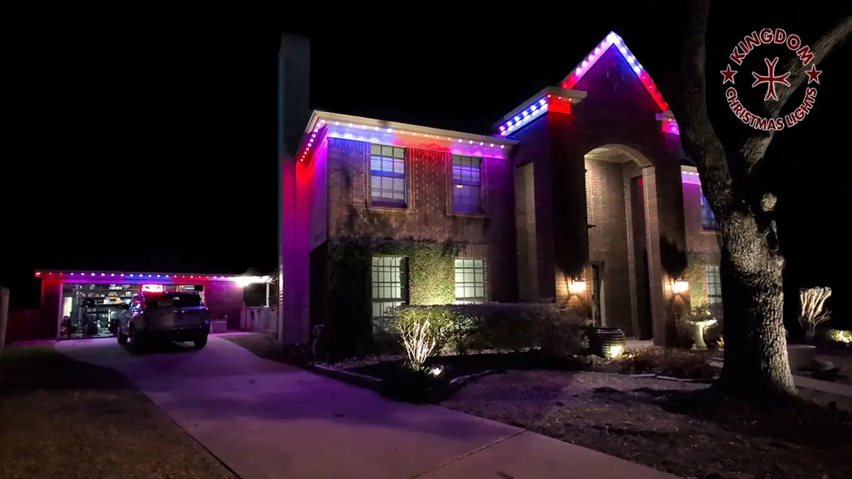 Home with red, white, and blue permanent roofline lights at night.