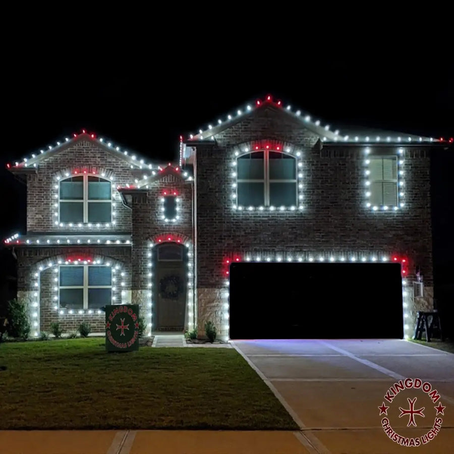 Two-story brick house decorated with Christmas lights at night.