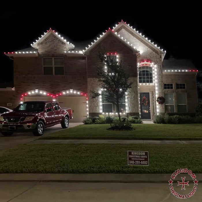 House decorated with Christmas lights at night, with a truck parked in front.