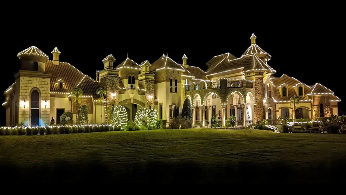 Large luxury home outlined with warm white Christmas lights at night