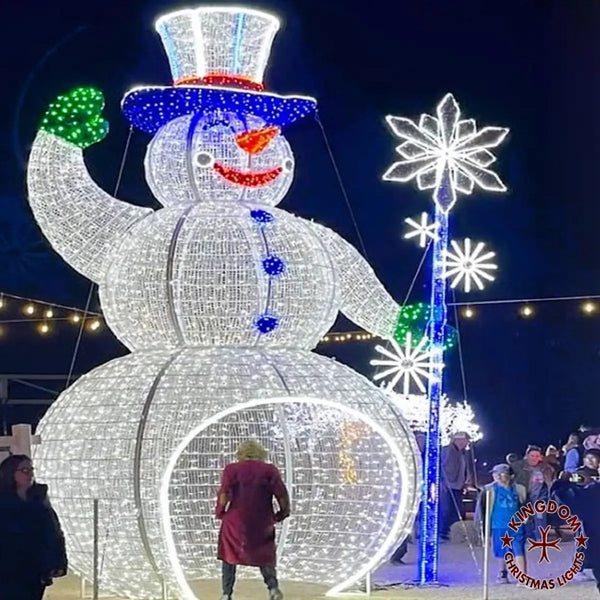 Large illuminated snowman sculpture with people around at night